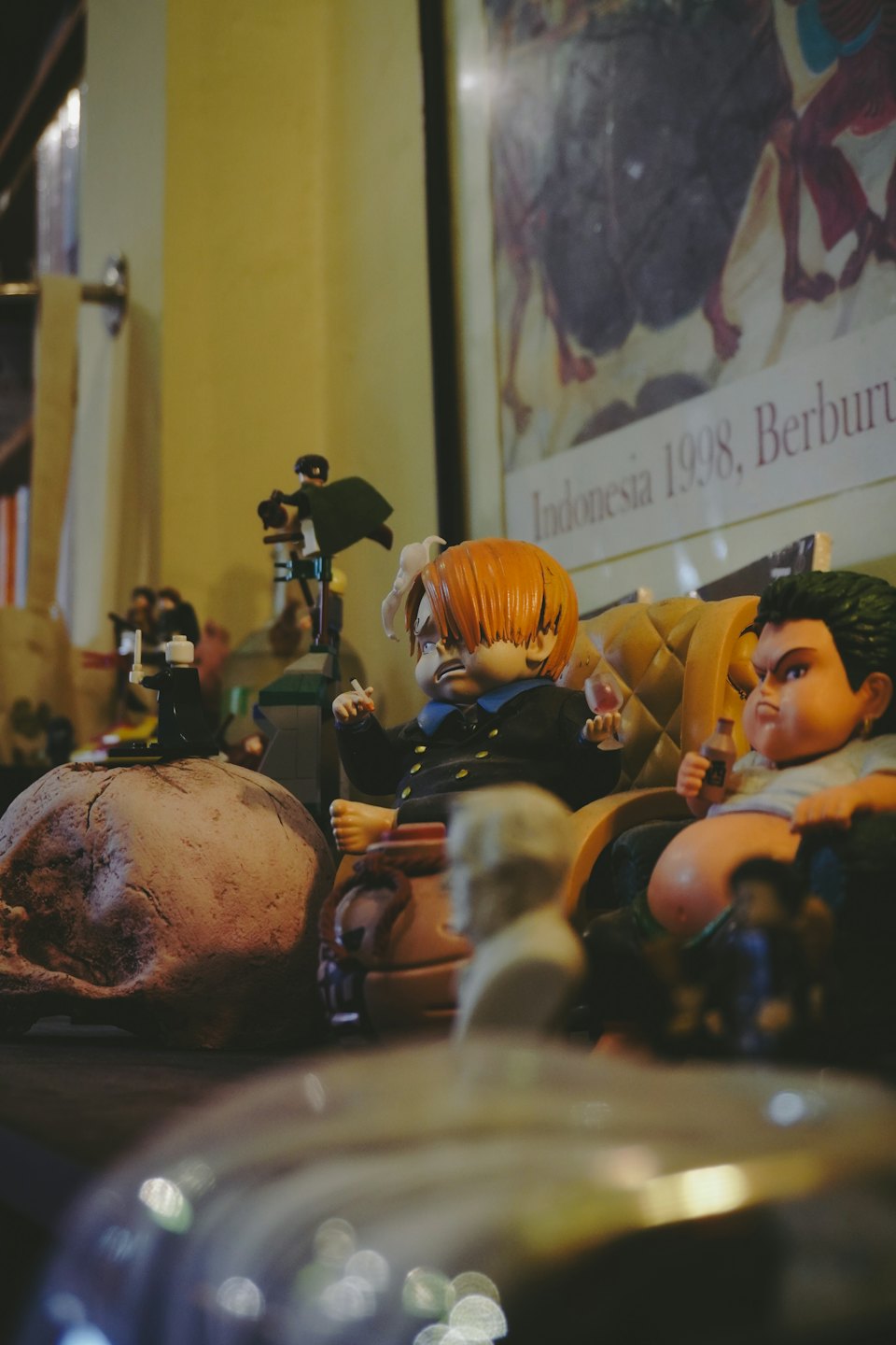 Anime-Figuren sitzen neben einem Totenkopf auf einem Regal.