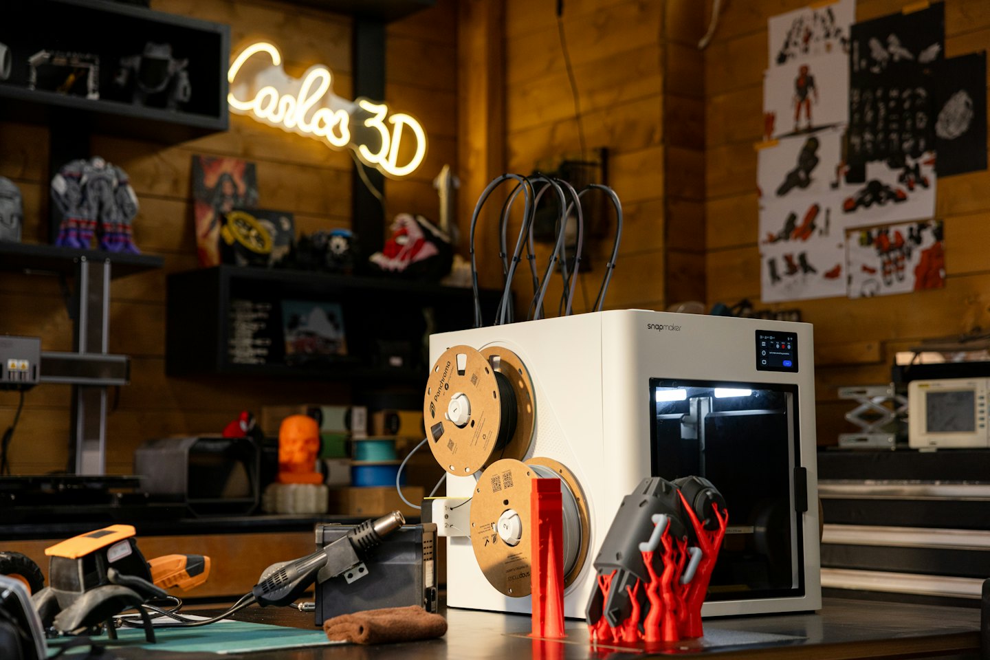 Ein moderner 3D-Drucker erstellt ein rotes Objekt auf einer Werkbank.