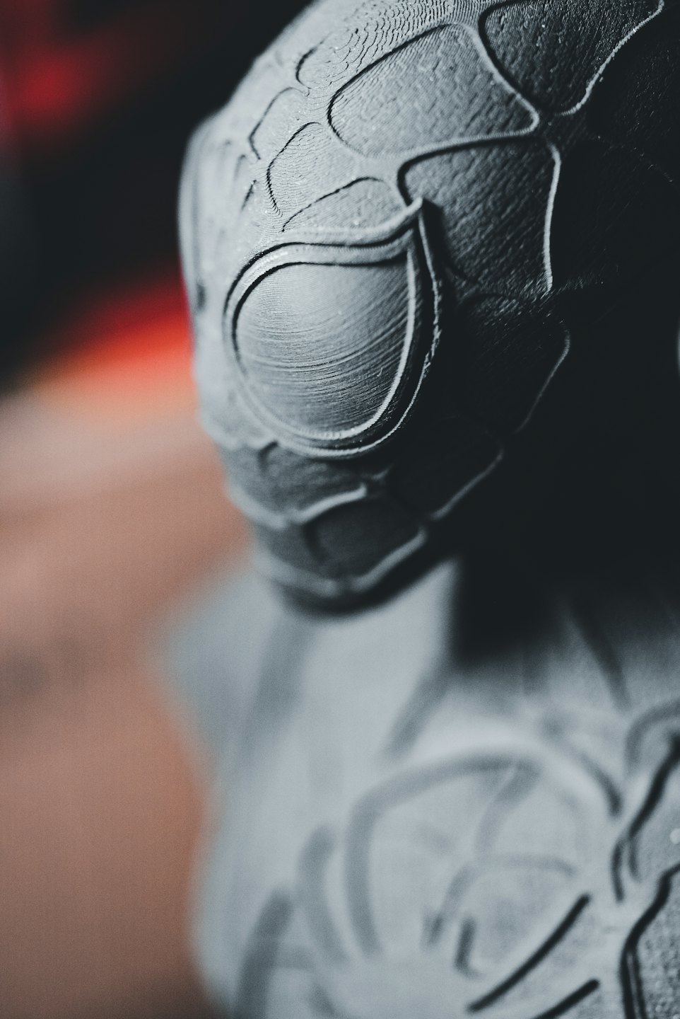Graue 3D-gedruckte Maske mit sichtbaren Schichtlinien und texturierter Oberfläche.