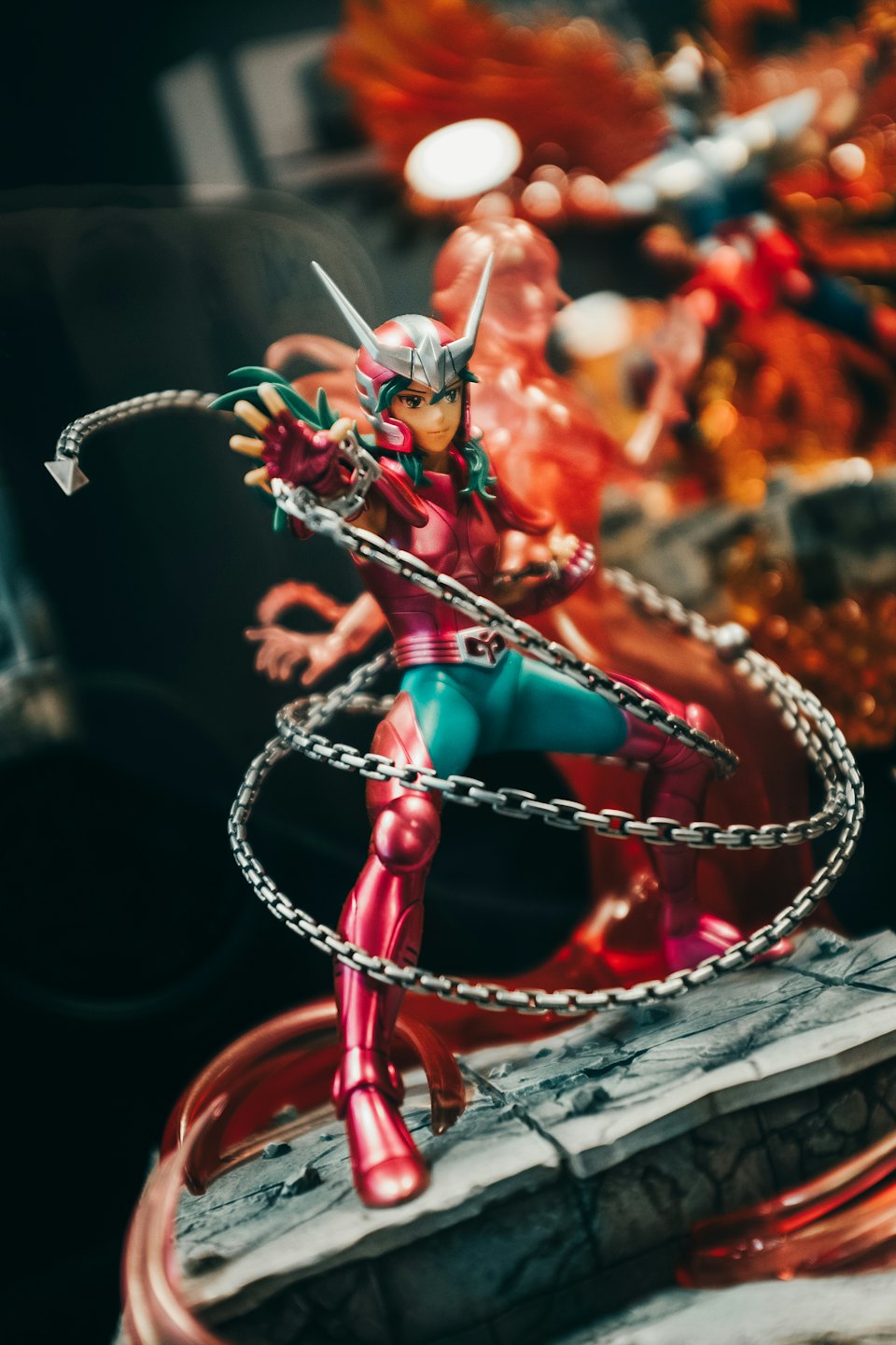 Anime-Actionfigur in pinker und türkiser Rüstung hält eine Kette.